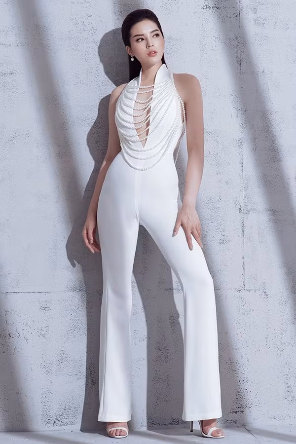 Bộ jumpsuit với chi tiết xẻ sâu nhằm giúp người mặc khoe khéo vòng một. Trang phục còn thu hút ánh nhìn nhờ chuỗi hạt giả ngọc trai được đính liền trên thân áo.