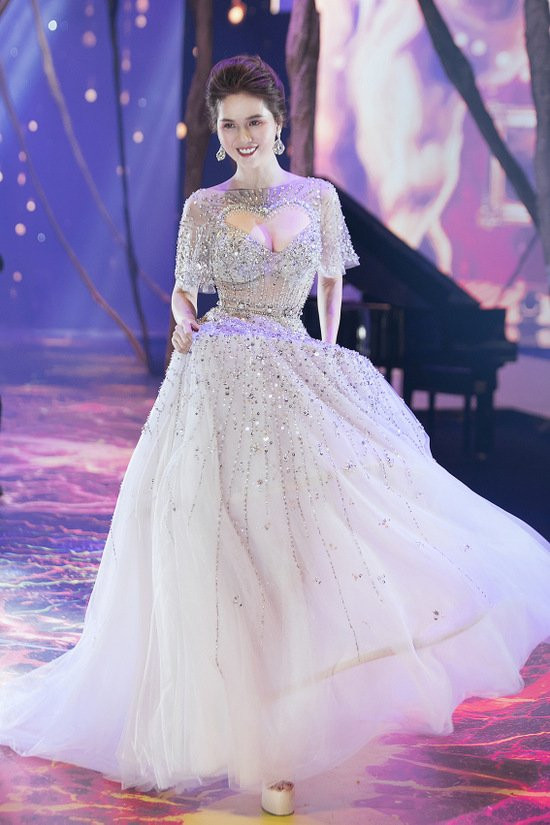 Cũng trong show diễn này, người mẫu Ngọc Trinh sau đó lại xuất hiện như một nàng công chúa với đầm xòe điệu đà được đính đá cầu kì. Nàng thơ bikini sải bước đầy tự tin mở màn cho show diễn.