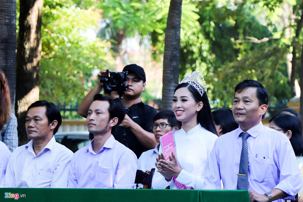 Ngồi cạnh Tiểu Vy là thầy hiệu trưởng Thái Văn Thanh (phải). Tất cả hoạt động của Tiểu Vy tại Hội An dịp này đều được ghi hình để làm tư liệu khi cô dự thi Hoa hậu Thế giới vào tháng 12 năm nay. Hôm qua (23/9), cô ghi hình tại một hiệu cao lầu ở Hội An, giới thiệu món đặc sản của quê hương mình ra thế giới.