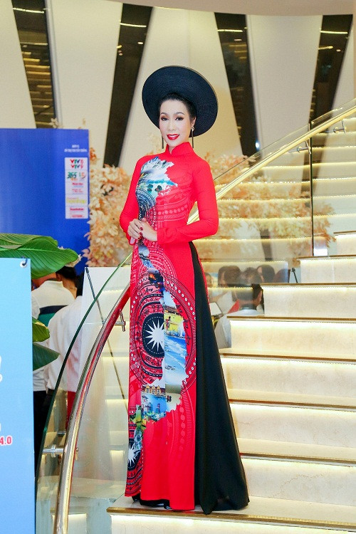 Trang phục áo dài màu đỏ rực với họa tiết trống đồng giúp Trịnh Kim Chi vô cùng nổi bật.