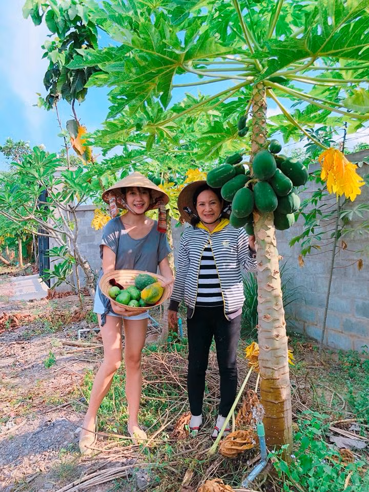 Minh Hà khoe một nón đựng đầy đu đủ xanh và chín.