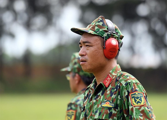 Một thành viên Ban huấn luyện đang hướng dẫn các xạ thủ trên thao trường.