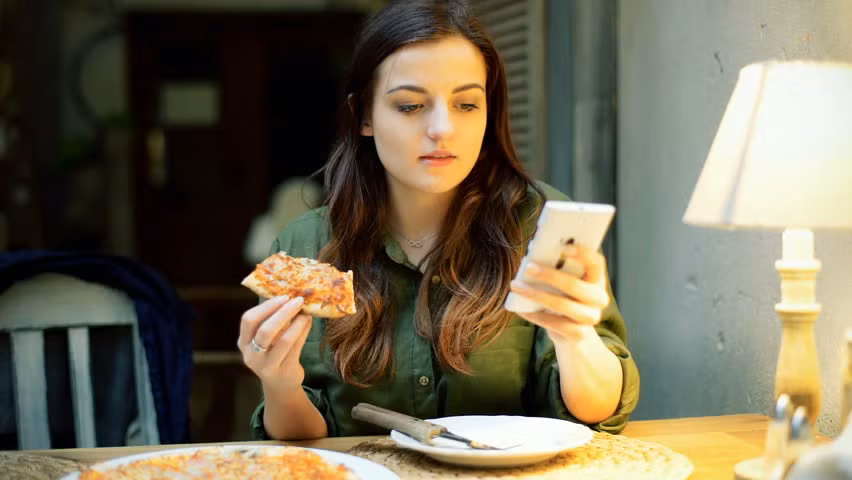 Vừa ăn vừa sử dụng điện thoại hoặc xem tivi là thói quen xấu khi ăn cơm rất nhiều người Việt mắc phải. (Nguồn Picdn)