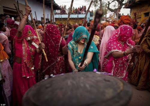 Những người đàn ông ném bột màu vào nhóm nữ, các bà các cô sẽ đánh đuổi họ bằng gậy tre.