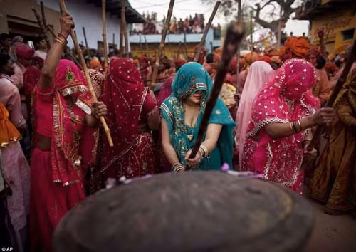 Những người đàn ông ném bột màu vào nhóm nữ, các bà các cô sẽ đánh đuổi họ bằng gậy tre.