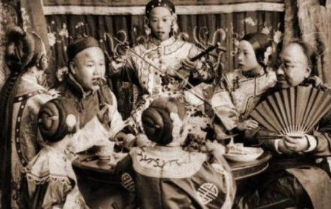 Hai thương nhân giàu có thời nhà Thanh vừa ăn uống vừa nghe đàn hát.