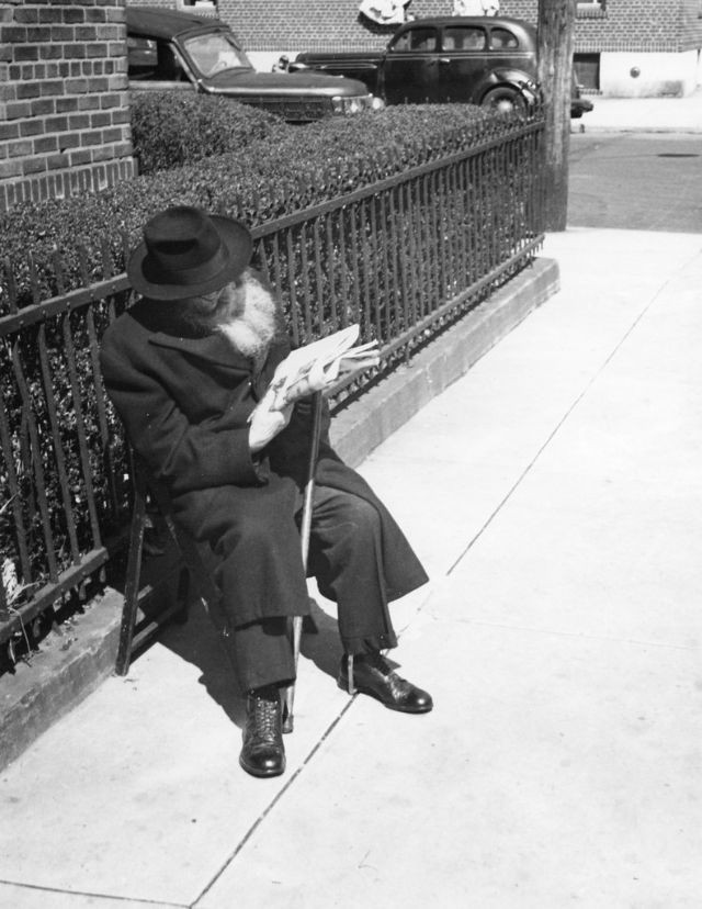 Một ông lão ngồi đọc báo ngoài trời.