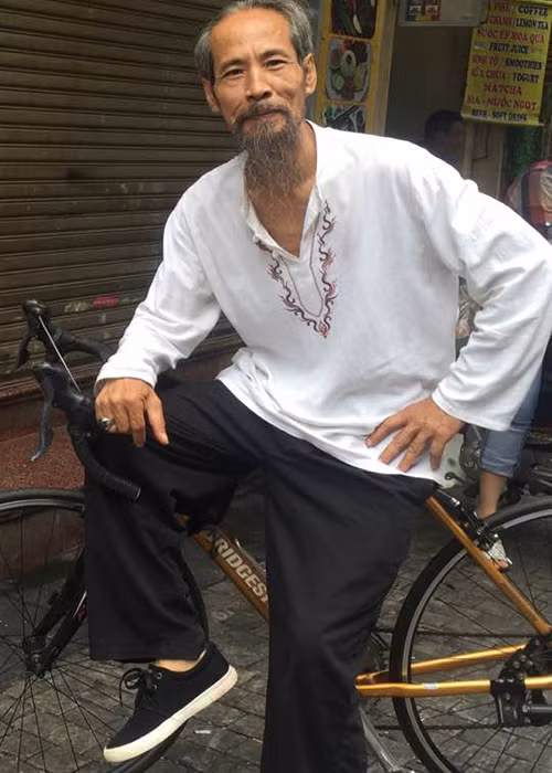 Ngoài đời, diễn viên Chu Hùng nuôi râu dài, ăn mặc giản dị như áo nâu, guốc mộc. Mỗi sáng, ông đều đạp xe gần nhà. Ảnh: FBNV