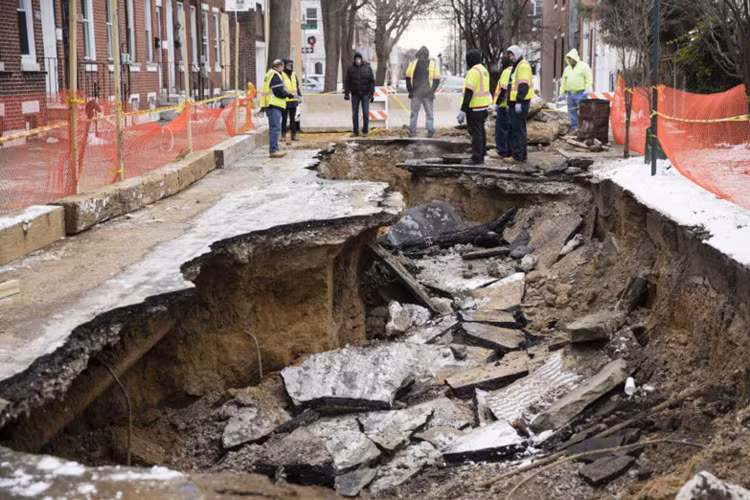 Công nhân đang kiểm tra vụ sụt đất nghiêm trọng ngày 9/1 tại Philadelphia, Mỹ. Nhà chức trách cho biết nguyên nhân là do một đường ống nước chính đã bị vỡ. Để đối phó với hiện tượng này, nhiều thiết bị máy móc hiện đại phát sóng radar xuyên đất và xử lý số liệu khoa học nhằm đo đạc, phát hiện phần đường bị sụt lún đã ra đời. Ảnh: AP.