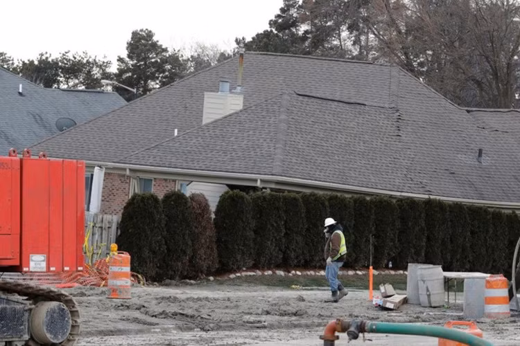 Một công nhân xây dựng đi qua ngôi nhà bị "hố tử thần" nuốt dở ở Fraser, bang Michigan, Mỹ. Khi nhận thấy rung chấn hay bề mặt đất xói mòn, trũng, cây cối và nhà cửa nghiêng ngả, bạn có thể báo cho chính quyền và di chuyển khỏi địa điểm đó bởi rất có thể, hiện tượng sụt lún sẽ xảy ra. Ảnh: AP.