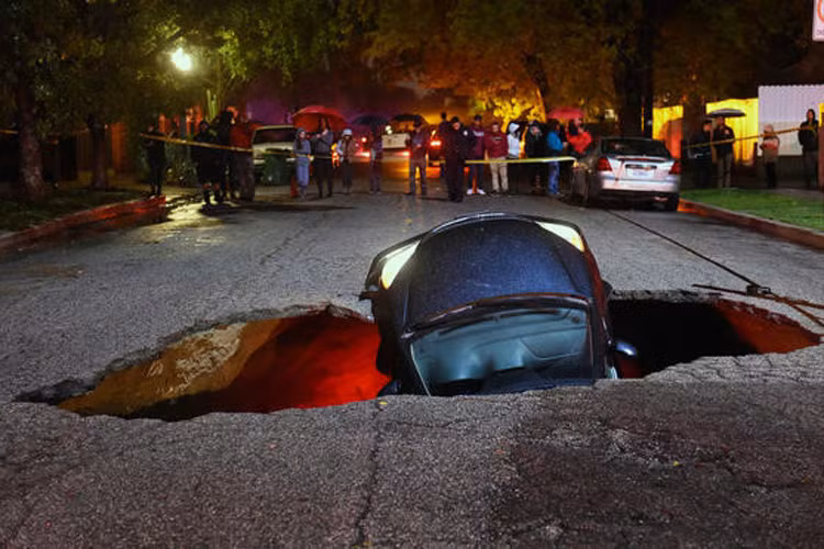 Ảnh chụp "hố tử thần" nuốt 2 chiếc xe ngày 18/2 tại Studio City, phía bắc Los Angeles, Mỹ. Cảnh sát đã rất vất vả để giải cứu các nạn nhân. Ngoài yếu tố địa lý, những hoạt động như xây dựng cơ sở hạ tầng, cầu cống, khai thác mỏ... cũng là tác nhân góp phần gây ra hiện tượng này. Ảnh: LA Times.