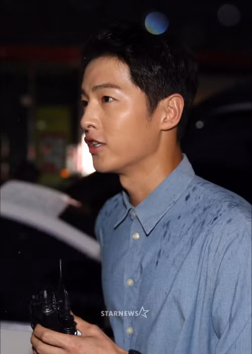 Mặc dù trời đổ mưa to nhưng Song Joong Ki vẫn dành thời gian trả lời báo chí truyền thông. Ảnh: Starnews