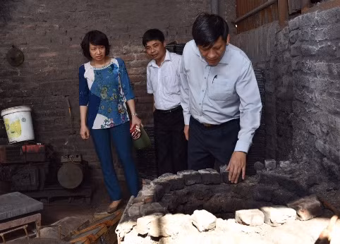 Thứ trưởng Bộ Y tế Nguyễn Thanh Long kiểm tra một lò nấu chì. Sau cuộc kiểm tra này, Bộ Y tế đã yêu cầu di dời ngay 13 hộ dân làm nghề tái chế chì còn lại ra khỏi thôn Đông Mai.