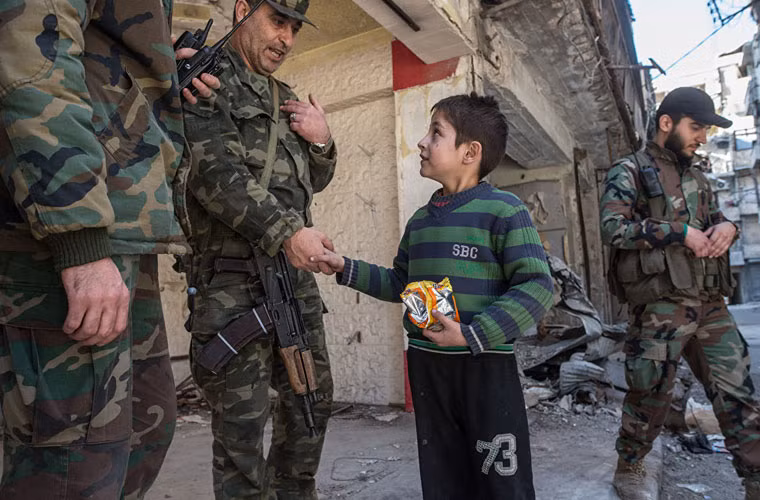 Bé trai trò chuyện với các binh sỹ ở Aleppo.