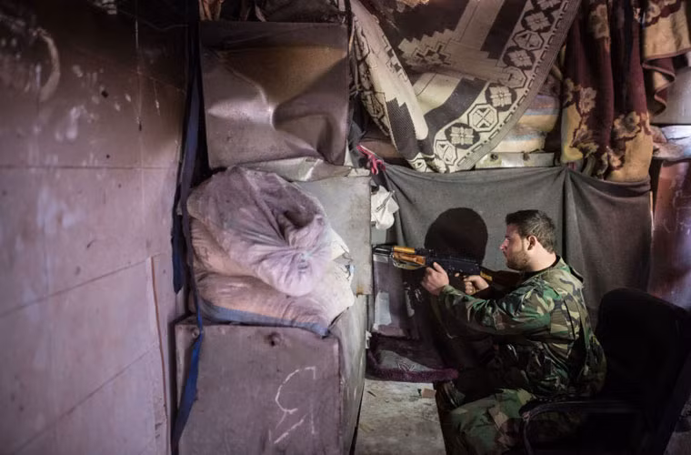 Một người lính Syria đang bắn đạn từ trong công sự.