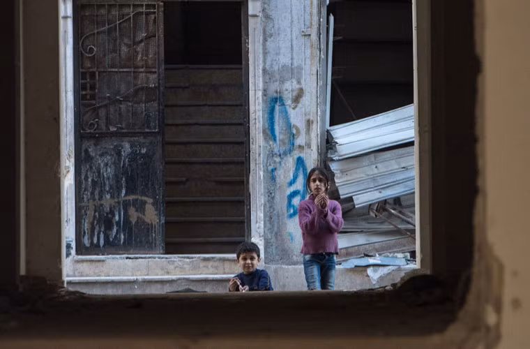 Các em nhỏ vui đùa trong những căn nhà đổ nát sau các trận đánh.