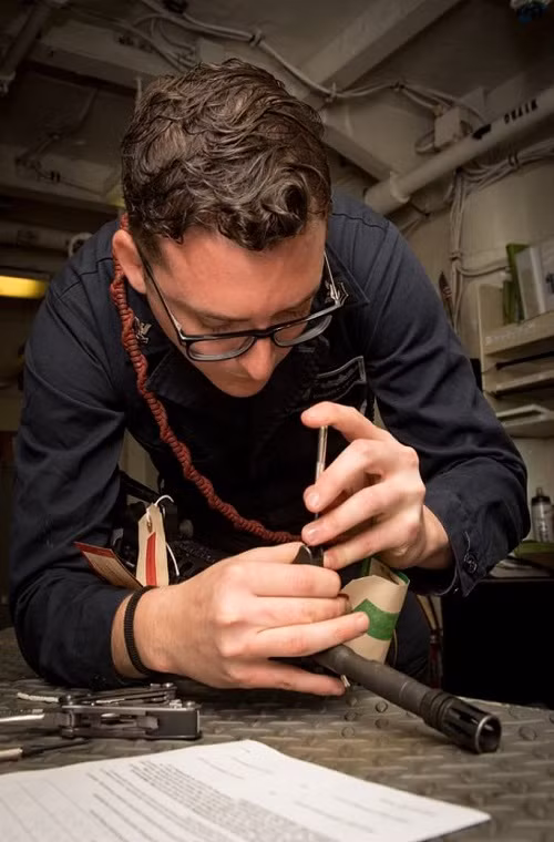 Một thủy thủ đang tranh thủ sửa chữa lại khẩu súng carbine M4A1 trong tàu sân bay. Nguồn ảnh: US Navy.