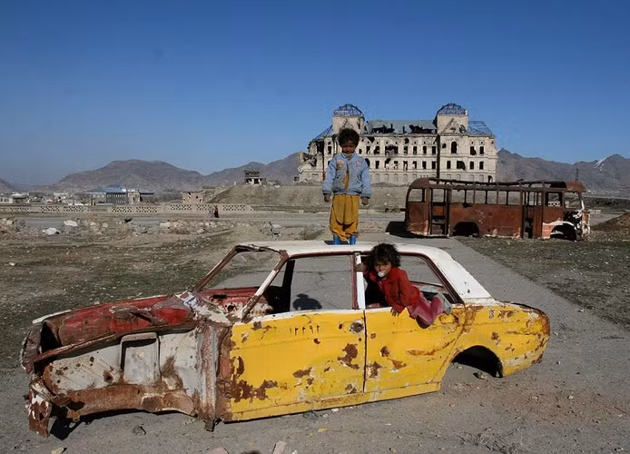 Hai đứa trẻ chơi đùa với một chiếc xe bị phá hủy ở thủ đô Kabul của Afghanistan năm 2007.