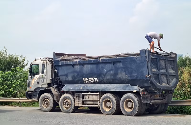 Tài xế này khi bị lực lượng chức năng dừng xe kiểm tra, thì vội vàng trèo lên thùng dùng xẻng san gạt, "cắt" ngọn cát đang chở.