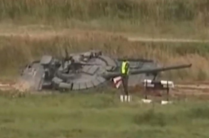 Chưa hết, một chiếc xe tăng chủ lực T-80BVM mang cờ xanh dương xuất phát cuối cùng trong số 4 xe tham gia cuộc đua biểu diễn. Tuy nhiên sau khi hoàn thành bài thi đi dích dắc vượt hàng cọc tiêu, chiếc T-80BVM này lao sang vệ đường, sa xuống ruộng và nghiêng hẳn sang một bên.