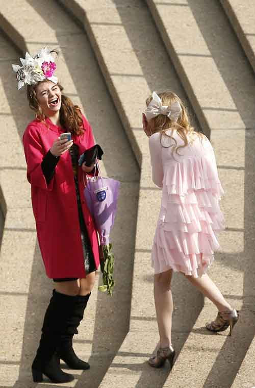 Hai cô gái ăn diện đang cười lúc trò chuyện với nhau.