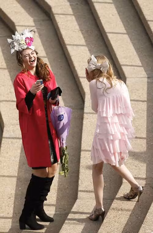 Hai cô gái ăn diện đang cười lúc trò chuyện với nhau.