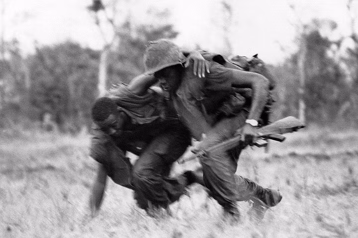 Một lính thủy đánh bộ Mỹ dìu đồng đội bị thương tới nơi ẩn nấp trước hỏa lực của quân giải phóng Việt Nam ở vùng tây nam khu phi quân sự giữa 2 miền. Ảnh: AP.