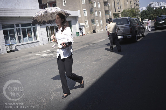 Người phụ nữ Triều Tiên cầm ô che nắng đi ngang qua một cửa hàng bách hóa.