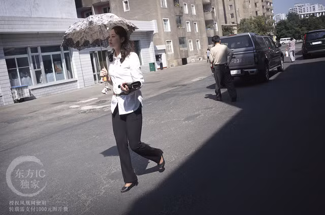 Người phụ nữ Triều Tiên cầm ô che nắng đi ngang qua một cửa hàng bách hóa.