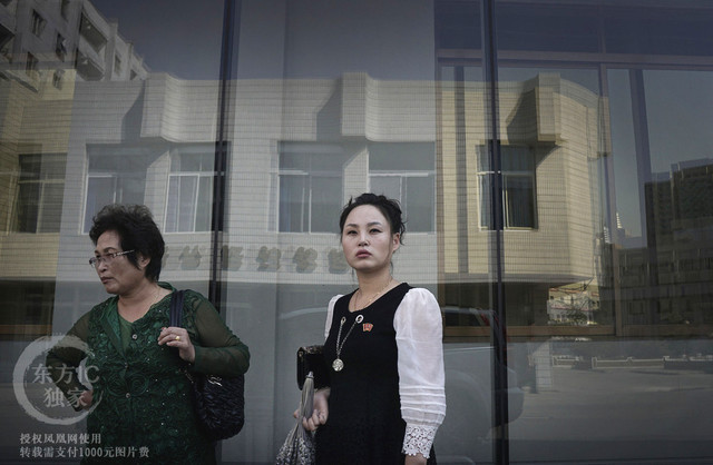 Hai người phụ nữ đứng đợi bên ngoài một hiệu bách hóa.