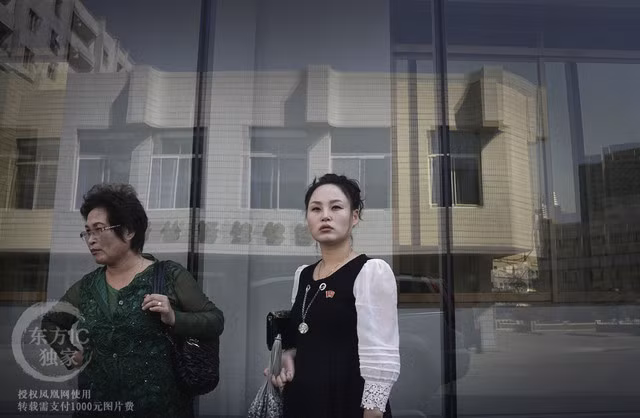 Hai người phụ nữ đứng đợi bên ngoài một hiệu bách hóa.