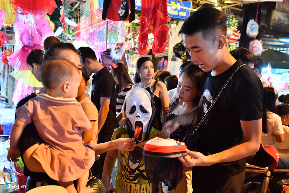 Một gia đình đang chọn mua cho trẻ nhỏ chiếc mặt nạ hình đầu lâu theo ý thích của con.