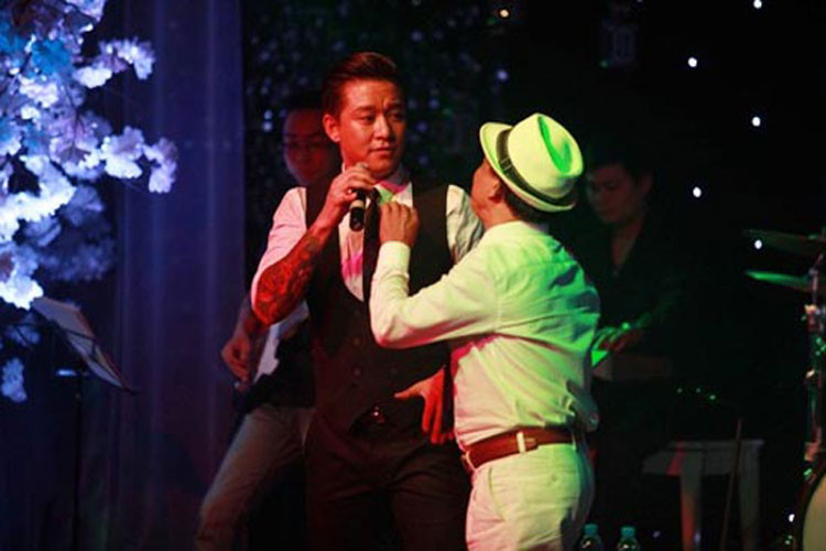 Đang tập trung hát theo yêu cầu của khán giả tại một đêm nhạc, Tuấn Hưng bị một khán giả đòi mic để song ca. Sau một hồi bối rối, nam ca sĩ chấp nhận để fan biểu diễn cùng mình. Ảnh: Vietnamnet