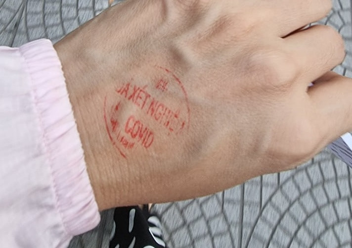 Sau khi test nhanh sẽ được đóng dấu chứng nhận đã xét nghiệm COVID-19 vào tay.