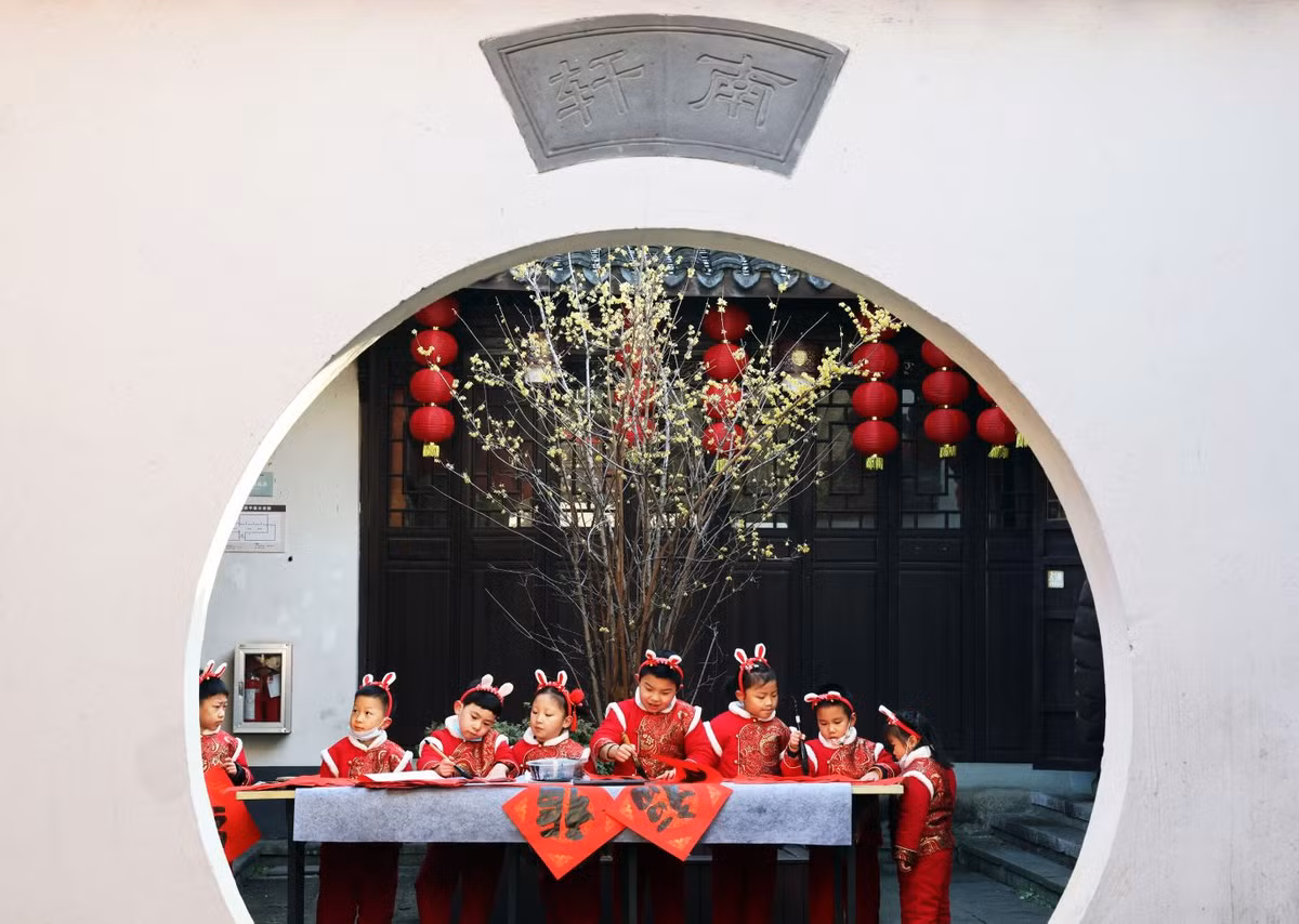 Trẻ em tại Hồ Châu, Trung Quốc tất bật chuẩn bị cho năm mới với những bộ trang phục màu đỏ và chiếc bờm cách điệu như tai thỏ.