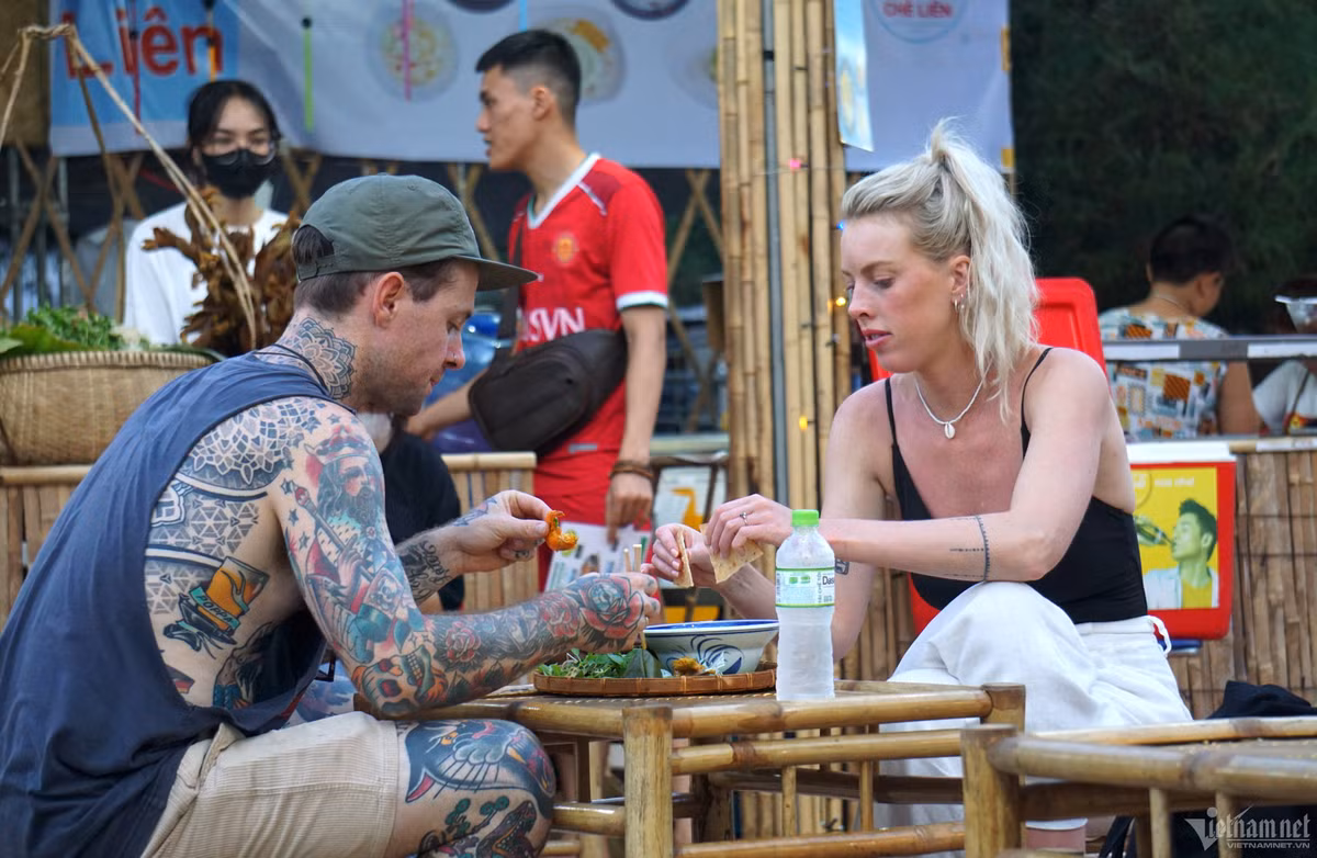 Tại không gian ẩm thực được bố trí sẵn bàn ghế để du khách ngồi ăn và xem trực tiếp đầu bếp chế biến. Khu vực trải nghiệm ẩm thực truyền thống được rất nhiều du khách trong nước và quốc tế ghé thăm Trong ảnh hai du khách quốc tế đang thưởng thức món mỳ Quảng.