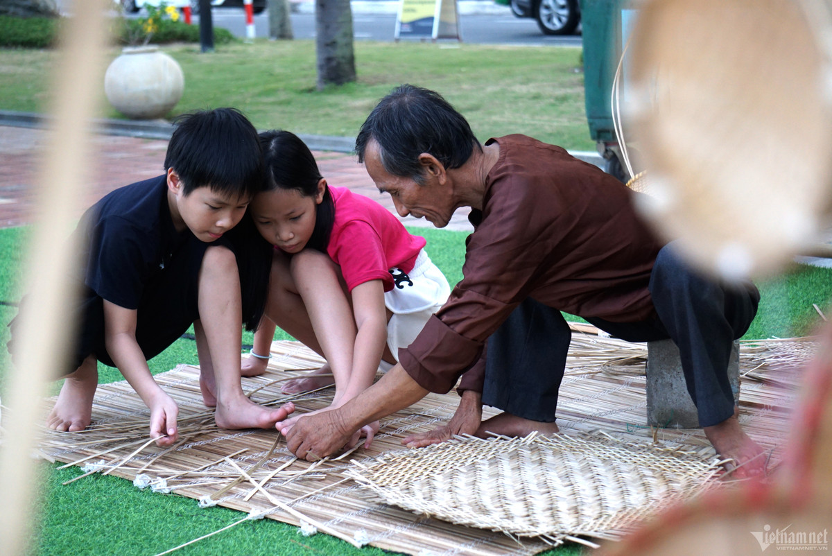 Hai du khách nhí thích thú tìm hiểu và trải nghiệm nghề đan lát mây tre truyền thống