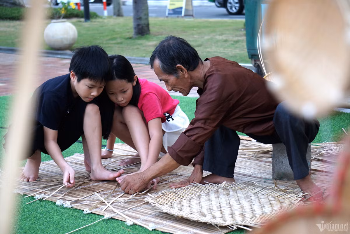 Hai du khách nhí thích thú tìm hiểu và trải nghiệm nghề đan lát mây tre truyền thống
