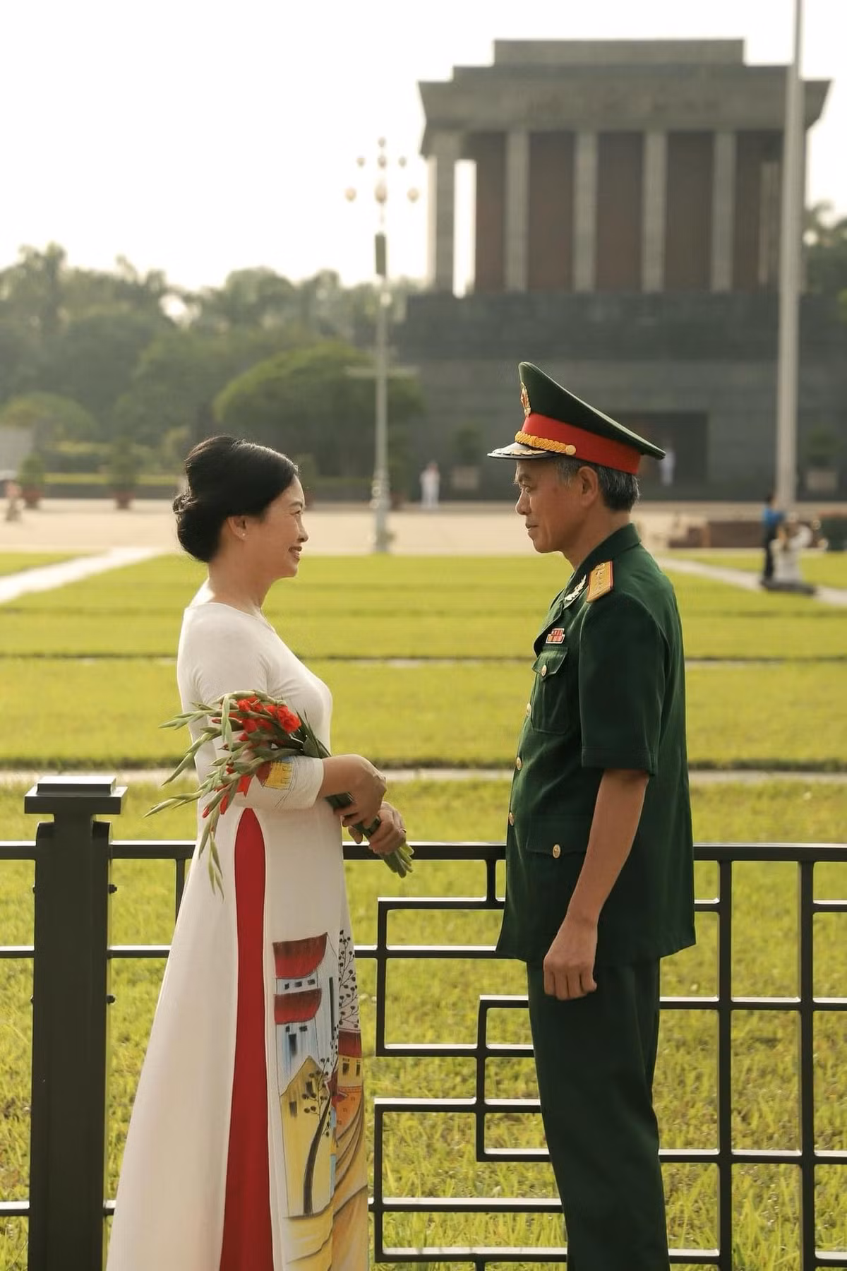 Cụ bà diện áo dài trắng, duyên dáng mà đằm thắm, thể hiện hình ảnh người hậu phương vững chắc cho chồng.