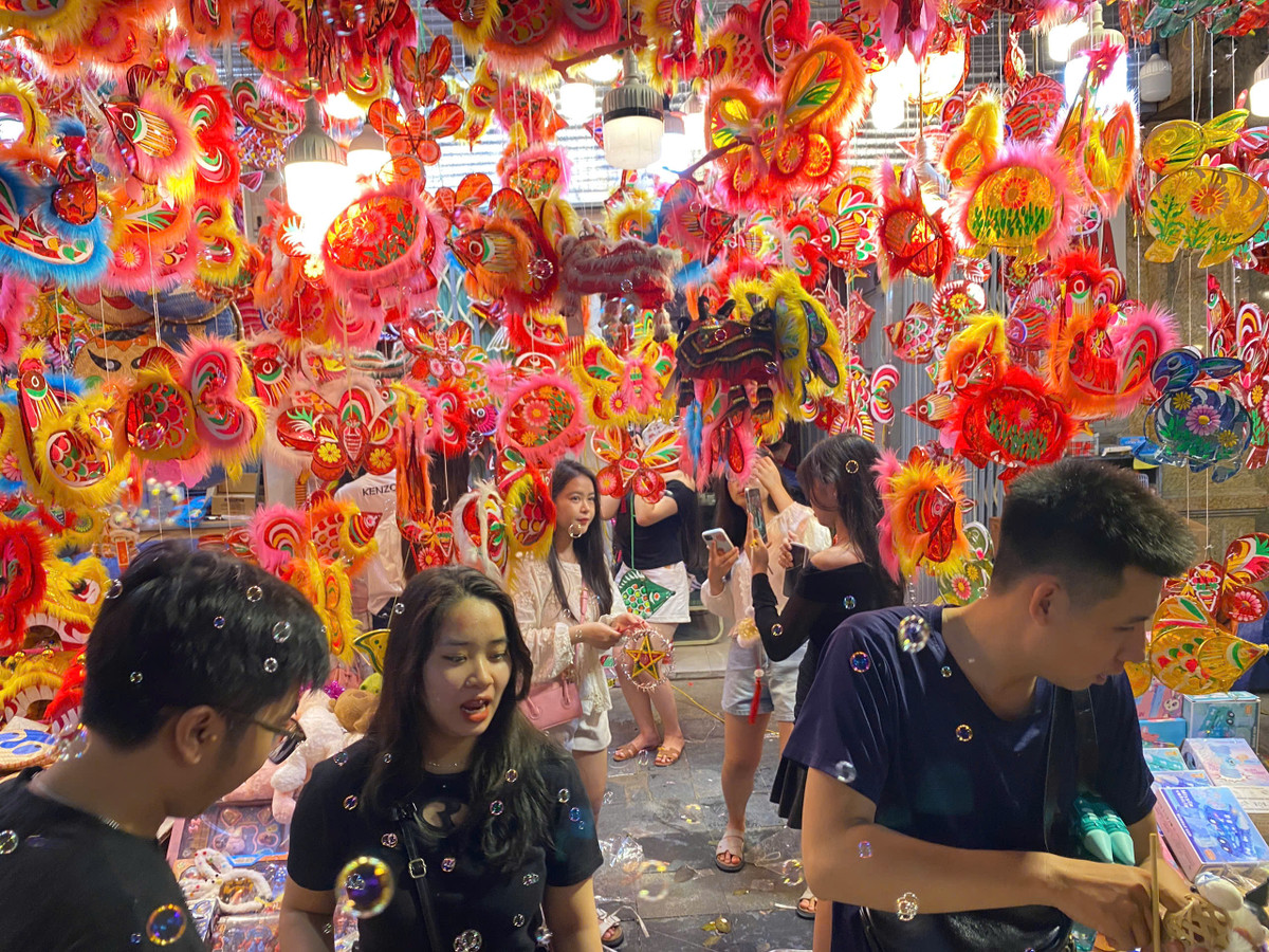 Nhiều bạn nữ đã xúng xính váy áo, mua 1 vài món đồ chơi nhỏ xinh để được chụp ảnh. Trong những hàng quán được treo nhiều đèn đủ màu và hình thù, rất đông người đứng xếp hàng chờ đến lượt để chụp hình.