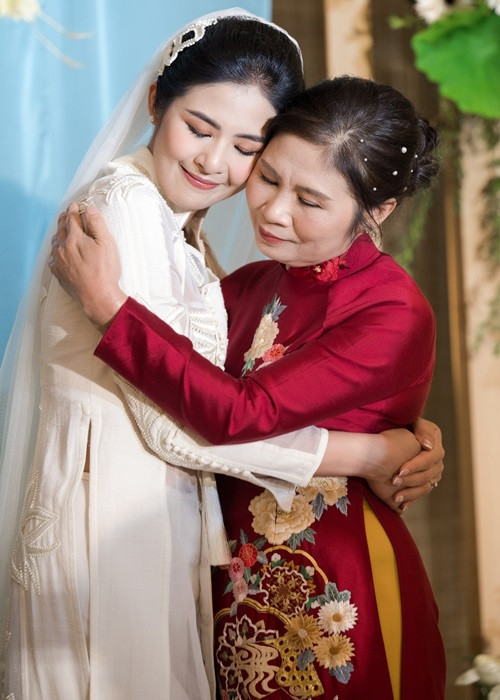 Mẹ đẻ của Ngọc Hân diện áo dài đỏ do con gái thiết kế. Ảnh: Zing