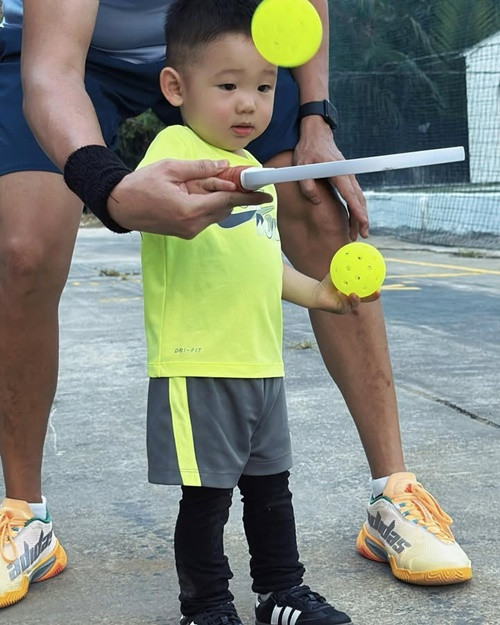 Bé Mỡ diện trang phục thể thao và được hướng dẫn đánh pickleball.