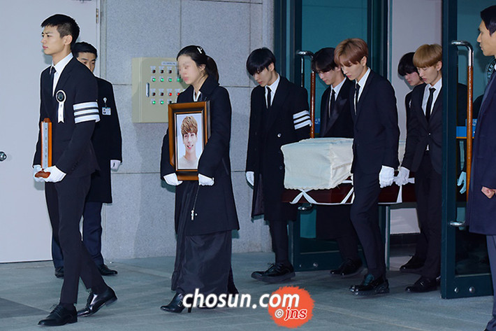 Minho (Shinee) ôm bài vị của Jonghyun. Trong suốt lễ viếng, Minho đảm nhận vai trò như một người thân.