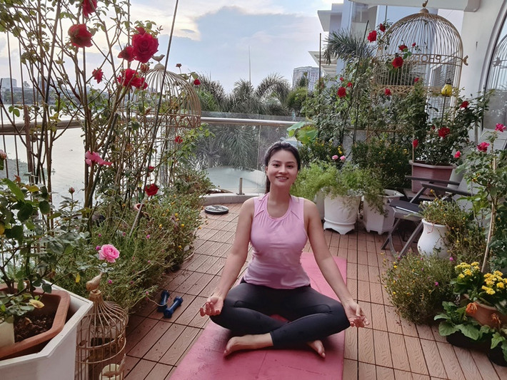 Nữ người mẫu ngồi thiền ở ban công ngập tràn hoa tươi.