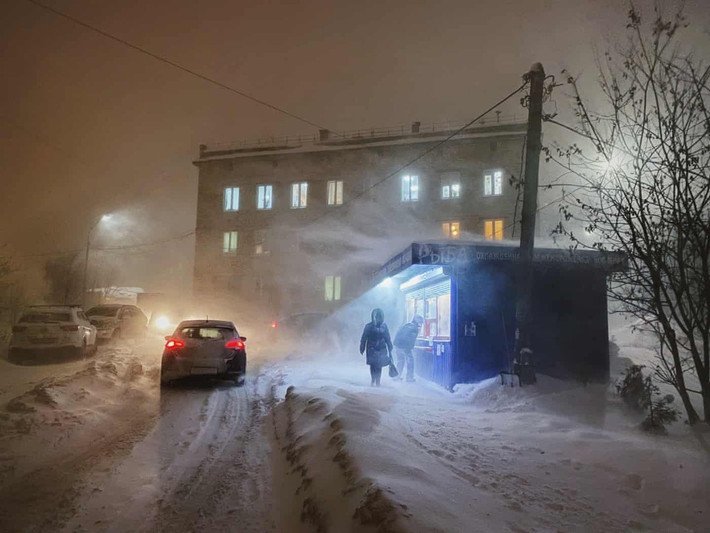 Một khách hàng nhìn vào trong tiệm bán cá giữa trận bão tuyết ở Murmansk.