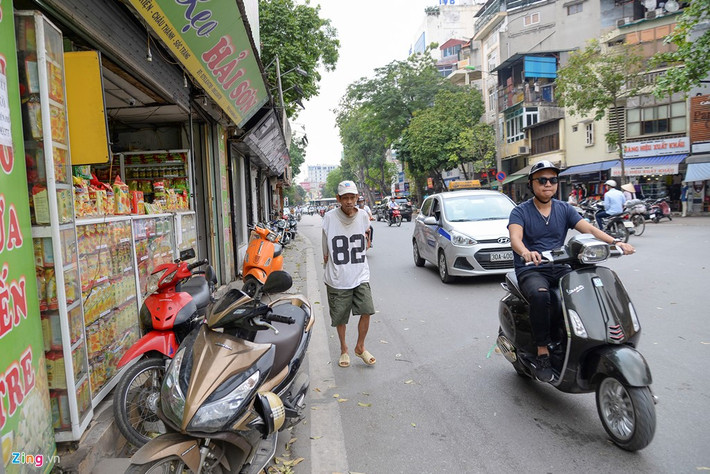 Người đi bộ hòa vào dòng phương tiện đang di chuyển dưới lòng đường.