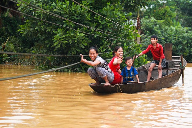 Phương tiện di chuyển duy nhất tại nơi đây là thuyền. Một gia đình đang vượt qua những dây điện chằng chịt để đến thăm hỏi nhà hàng xóm. Dù trong hoàn cảnh khó khăn, người miền Trung vẫn giữ được niềm lạc quan, vượt lên thử thách.