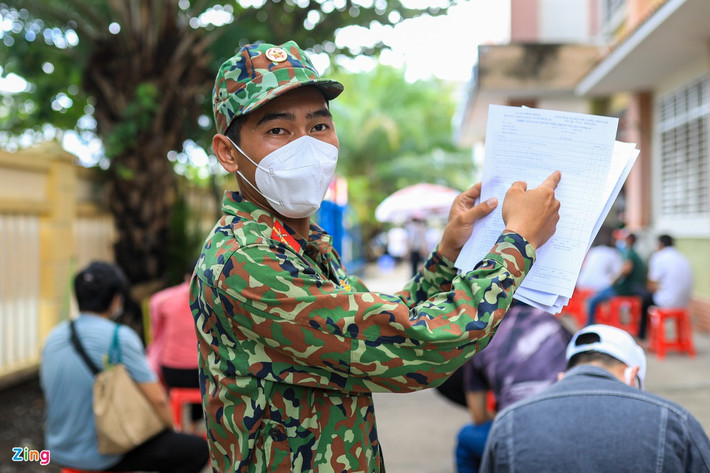 Bên trong trường học, người dân được lực lượng chức năng phát giấy và hướng dẫn điền thông tin cá nhân, khai báo y tế.