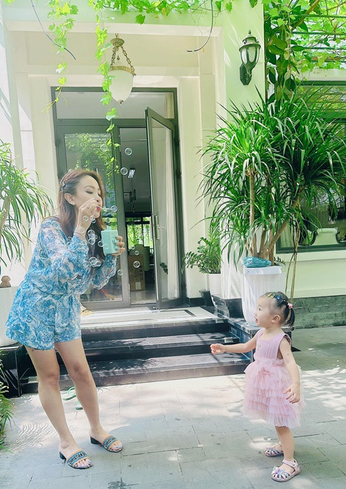 Nữ MC thổi bong bóng xà phòng để con gái chơi đùa trong sân nhà.