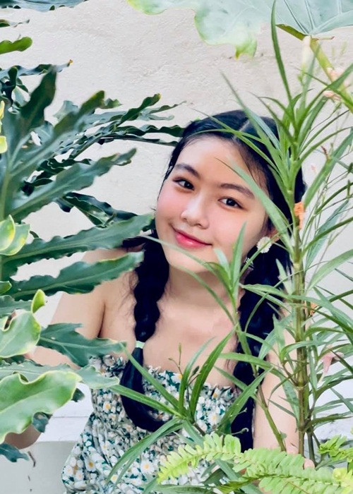 Lọ Lem diện đầm xanh, tóc tết 2 bên khoe sắc trong khu vườn trên sân thượng tại nhà.